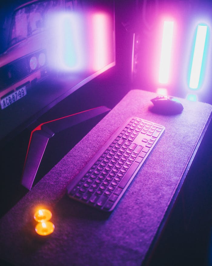 A vibrant desk setup featuring a computer keyboard, mouse, and colorful ambient lighting creating a modern tech atmosphere.
